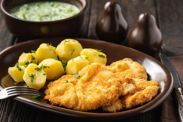 Chop pork cutlets , served with boiled potatoes and tzatziki dip. 