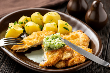 Chop pork cutlets , served with boiled potatoes and tzatziki dip. 