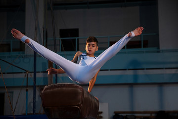 Little male gymnast training in gym, flexible and active. Caucasian fit little boy, athlete in...