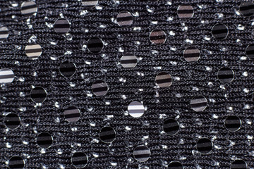 texture of black fabric (on clothes) with rhinestones, beads. Close-up (macro).