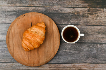 croissant and a cup of coffee on the table. Fresh french croissant. on a wooden background. View from above. Morning breakfast with a croissant. French breakfast Excellent homemade. Fresh tower.