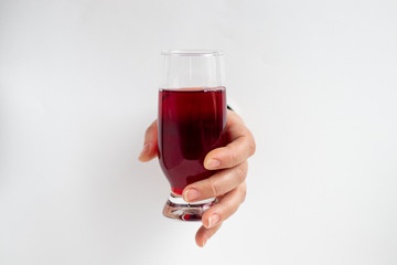Female hand holds a glass with cherry juice. Inserted into the hole in a sheet of paper. Healthy eating Copy space. 