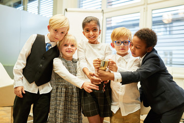 Gruppe multikultureller Kinder mit einem Sieger Pokal