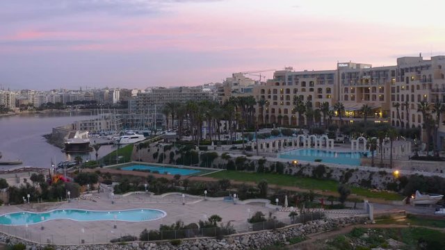 High Aerial shot orbiting around the coast of St Julians Malta. Baech at the sunset