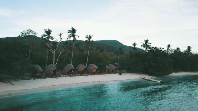 flying towards couple of bungalows on a beach