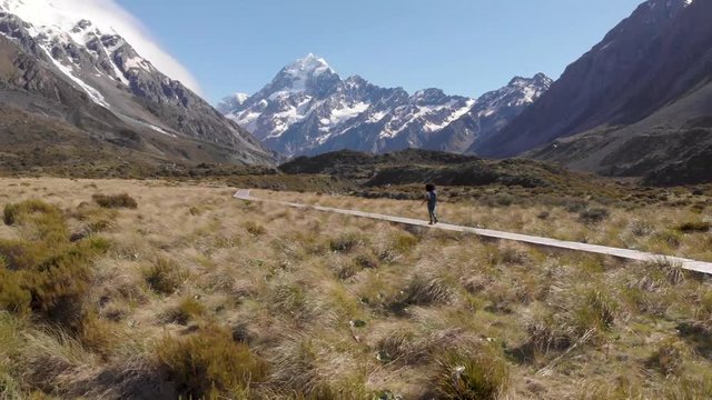 girl hinking towards mount cook new zealand fully visbible dolly in 4k grassland