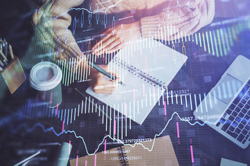 Forex graph on hand taking notes background. Concept of research. Double exposure