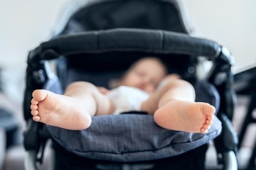 Cute adorable caucasian blond toddler bou sleeping in stroller at daytime. Children healthcare and...