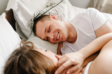 Fototapeta na wymiar A man caresses a woman in bed. Love couple lying in a big bedroom. Love story. Emotions of happiness. Enjoying spending time together. I love you.