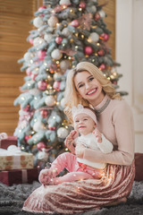 Obraz na płótnie Canvas Pretty woman with little daudgter sits under christmas tree
