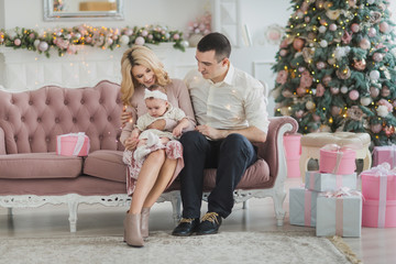 Happy young family in luxury baroque style interior near new year tree
