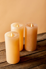 Obraz na płótnie Canvas three burning candles on wooden table on beige