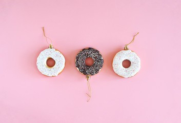 Christmas decoration donuts on a pastel pink background. New Year and Christmas creative concept. Top view, flat lay.
