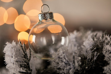 decorative transparent christmas ball on spruce branches in snow with blurred yellow lights © LIGHTFIELD STUDIOS