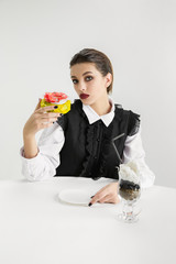 We are what we eat. Woman with cake and cocktail made of plastic, eco concept. There is so much polymers then we're just made of it. Environmental disaster, fashion, beauty, food. Loosing organic