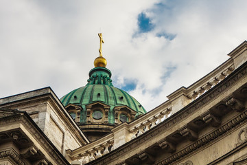 Close-up of the dome of the Kazan Cathedral with a golden cross part of a wall with columns and a frieze with windows, porticoes on a clear day.  St Petersburg, Russia