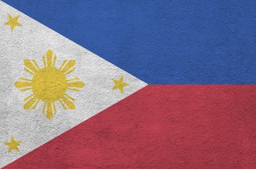 Philippines flag depicted in bright paint colors on old relief plastering wall. Textured banner on...