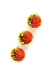 red caviar in dough tartlets with green salad on a white background