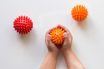 Spiky orange massage needle ball in child hands - obrazy, fototapety, plakaty