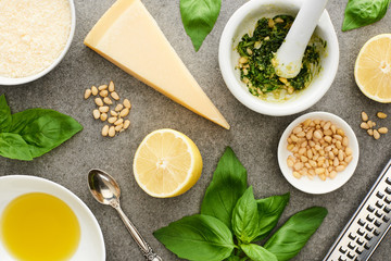 top view of pesto sauce raw ingredients and cooking utensils on grey surface