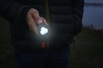 Man with flashlight walking outdoors, closeup view