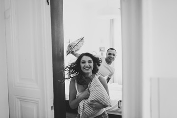 Fototapeta na wymiar Woman runs in door away from her husband. Love couple beats pillows. Emotions of happiness beautiful young couple. Enjoying spending time together. Lifestyle. Black and white photo.