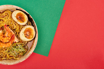 top view of spicy seafood ramen on green and red surface