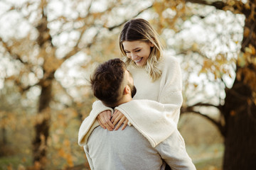 Fototapeta premium Young cheerful couple having fun in nature during autumn. Woman being carried by her boyfriend
