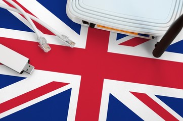 Great britain flag depicted on table with internet rj45 cable, wireless usb wifi adapter and...