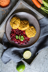 Fritters made from red lentils, carrot and rolled oats served with red onion and cabbage