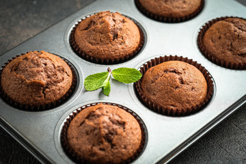 Chocolate muffins on a portioned board on a dark background top view.
