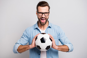 Photo of attractive handsome guy holding leather white black soccer ball yelling loud supporting team football match wear specs casual denim outfit isolated grey color background