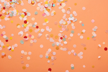 decorative and colorful confetti on orange background - obrazy, fototapety, plakaty