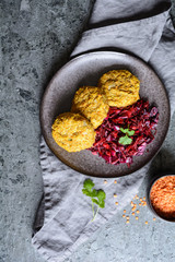 Fritters made from red lentils, carrot and rolled oats served with red onion and cabbage