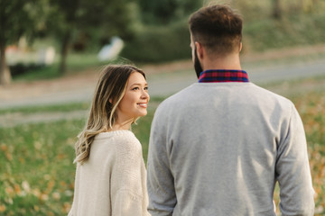 Obraz premium Smiling woman talking with her boyfriend while walking in the park