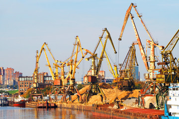 Fototapeta na wymiar Work of the cargo port, loading barges with sand