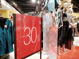 Sale in a fashionable boutique on black friday. Stand with percent discount and mannequins near the entrance