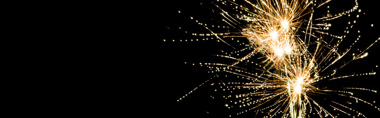 Panoramic shot of yellow traditional fireworks in night sky, isolated on black