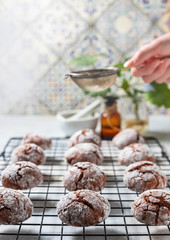 Cracked chocolate chip cookies in icing sugar. Chocolate christmas cookies on a white wooden table.
