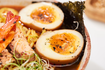 close up view of spicy seafood ramen with egg in bowl