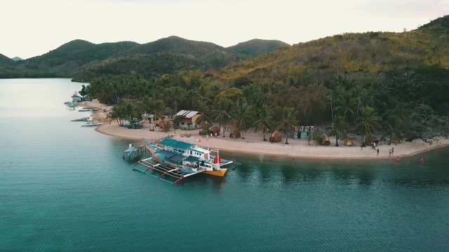 a bangka boat docked on a island close to a village and bungalows