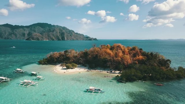 small island in the see with many local Banca boats float gently on the water