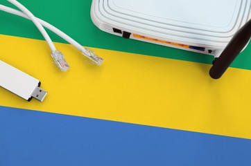 Gabon flag depicted on table with internet rj45 cable, wireless usb wifi adapter and router....