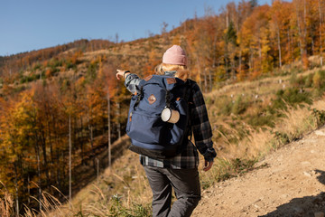 Hiker woman with backpack walking in the mountains in autumn scenery.