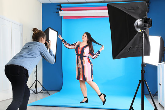 Photographer taking picture of overweight woman in studio. Plus size model