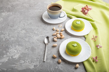 Green mousse cake with pistachio cream and a cup of coffee on a gray concrete background. side view, copy space.