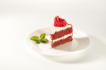 piece of cake Red velvet on a white background. Mint leaf as a decoration.