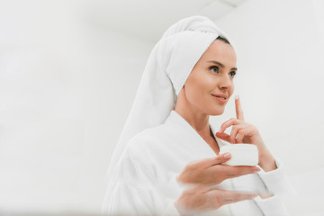 attractive woman applying cosmetic cream in bathroom