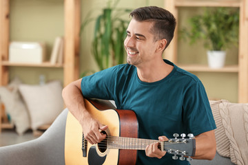 Obraz premium Handsome man playing guitar at home