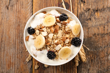muesli, cereal with banana and blackberry and milk on wood background